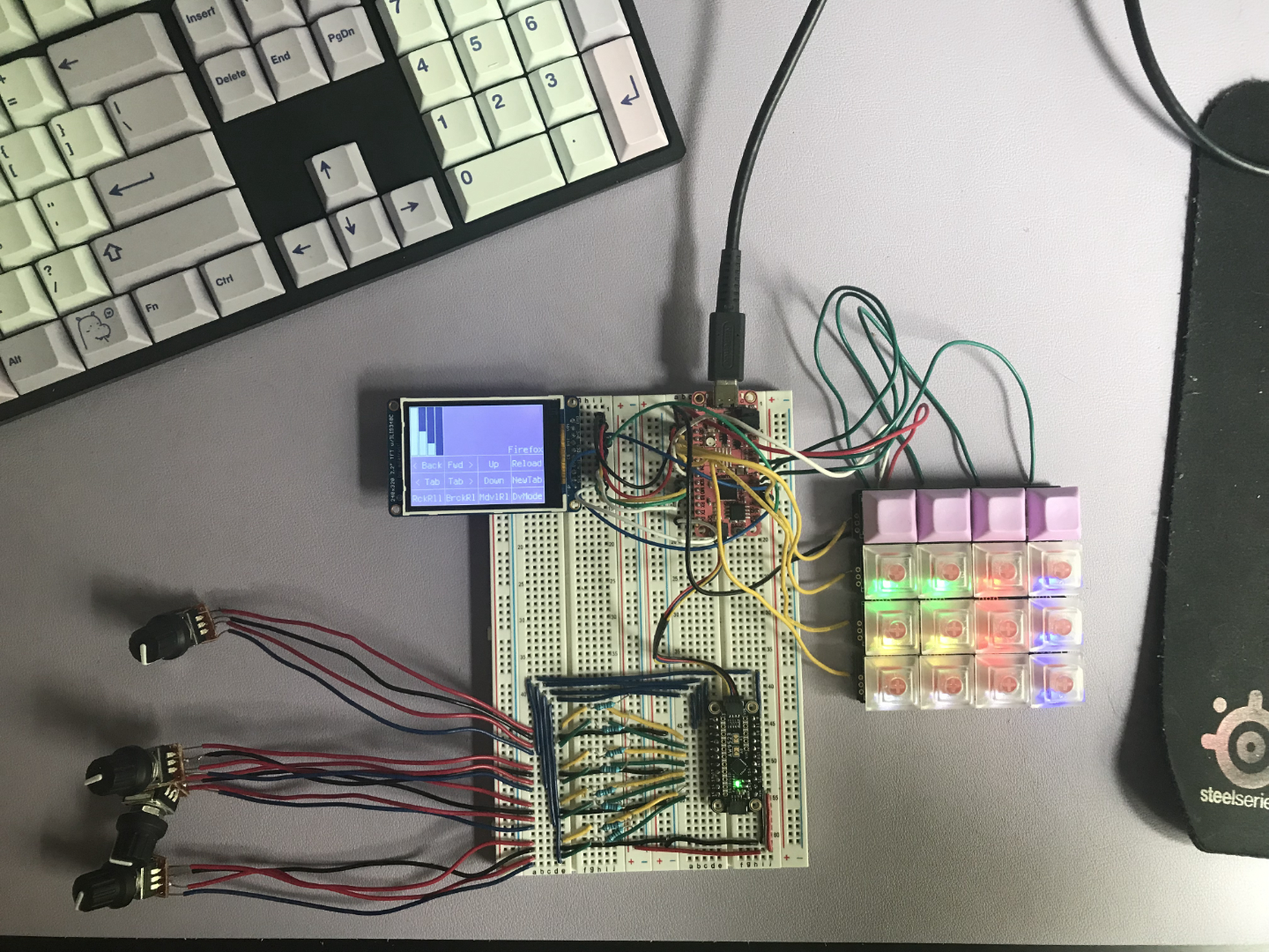 A mess of wires, components and breadboards. There's a keypad, four knobs, a screen, and a few controller boards